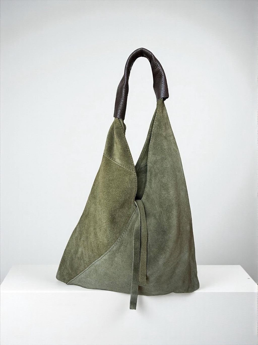 Close-up of leather-reinforced shoulder strap on suede bag