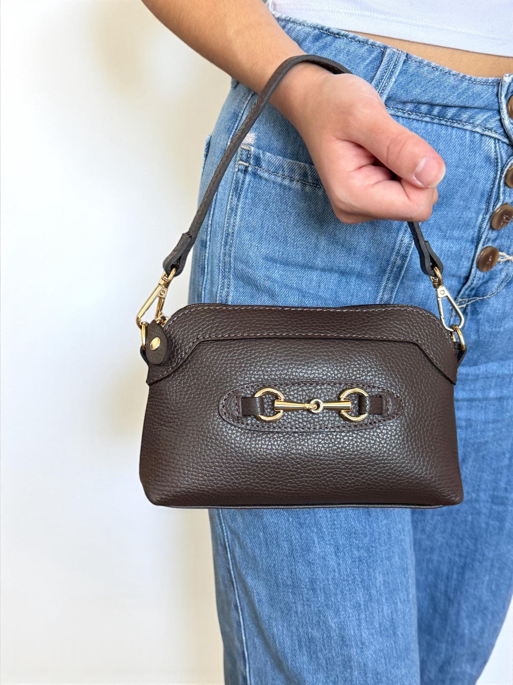 Close-up of gold-tone horsebit detail on brown Italian leather flap