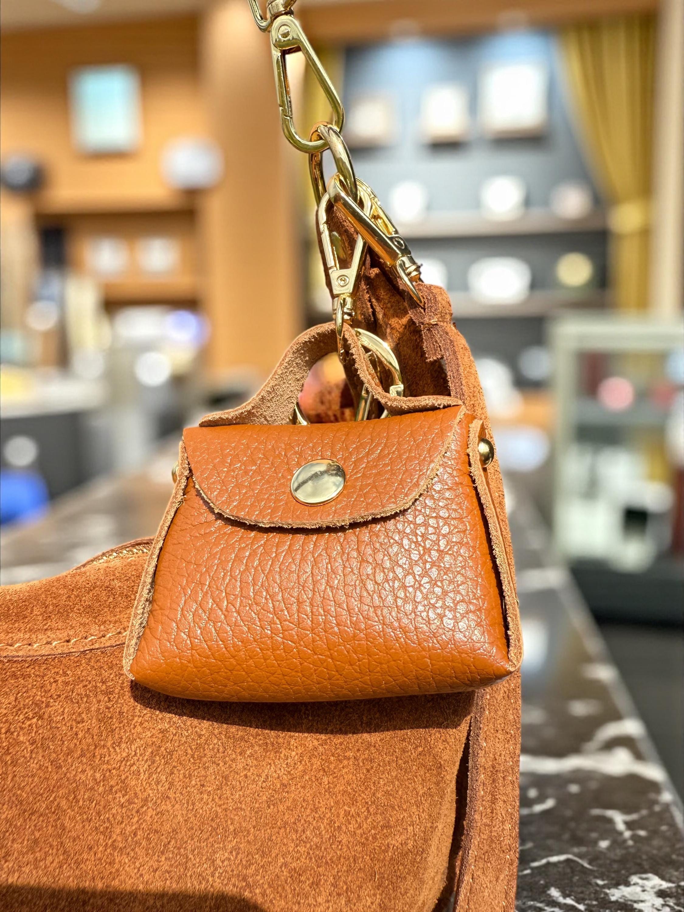 Miniature leather purse charm attached to a full-sized luxury tote bag Paloma Palomo