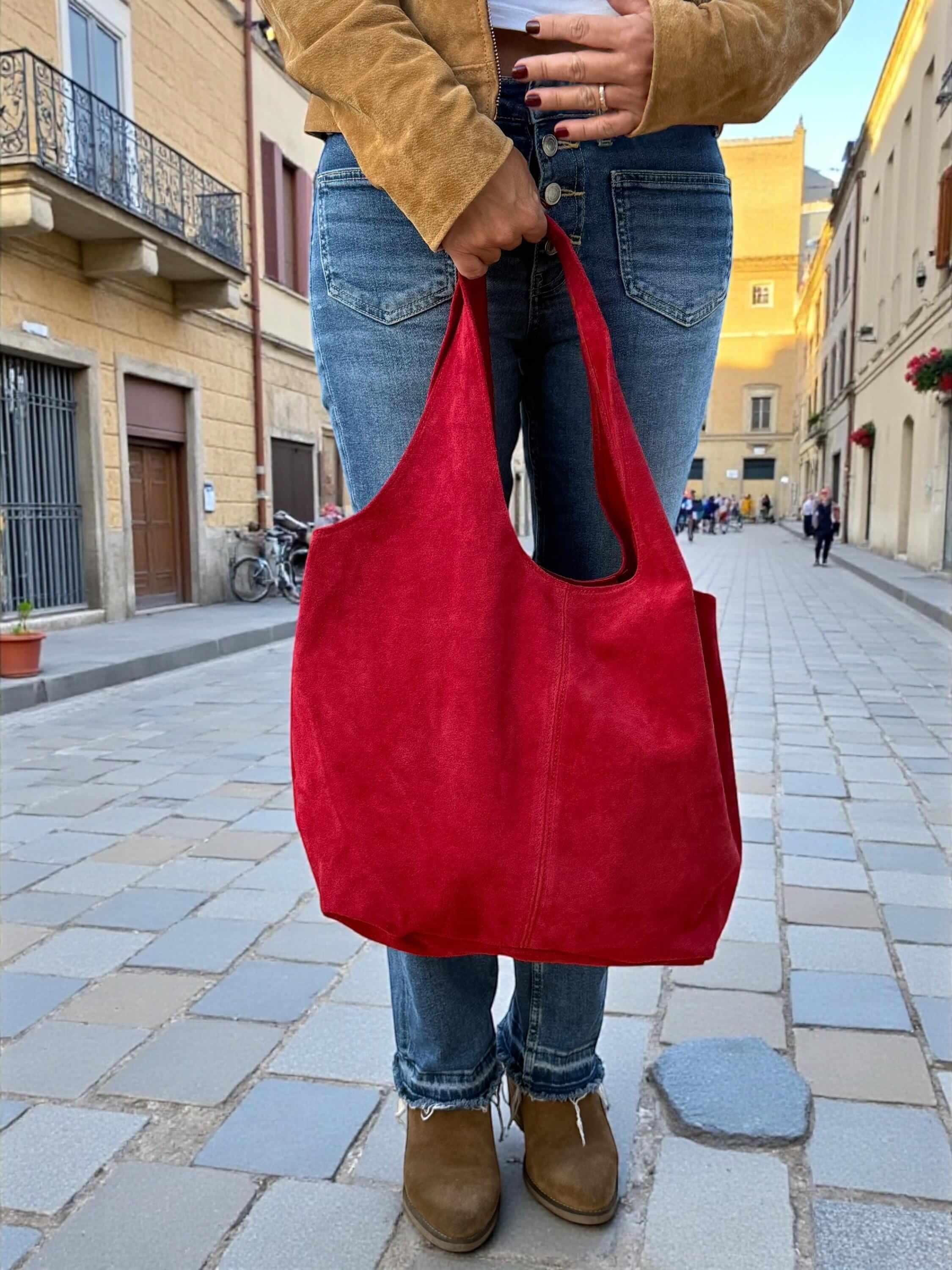 Oversized Red Suede boho Tote bag – University or office bag being held on a city street by a person in casual wear.