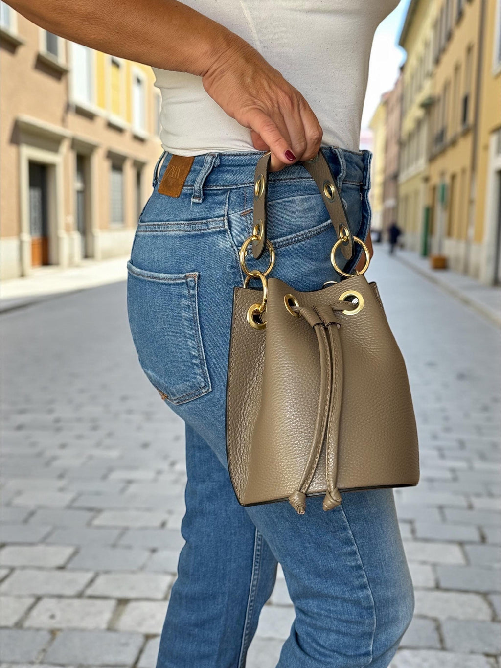 Woman wearing a small taupe bucket bag for a boho-luxe look