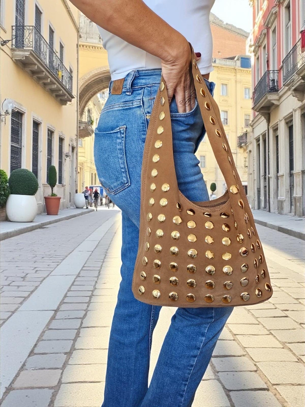 Woman wearing a studded suede hobo bag for a creative urban look