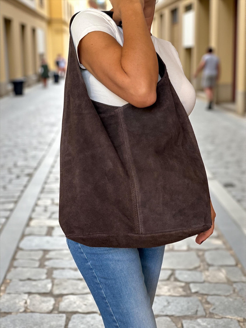 Woman wearing a slouchy dark brown suede bag with denim